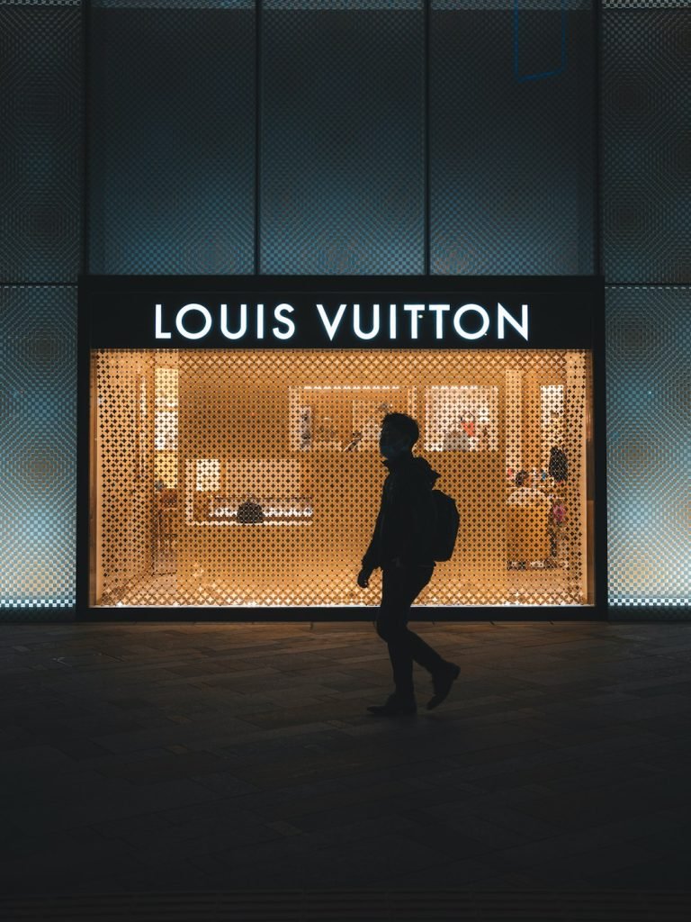 a-person-walking-in-front-of-a-louis-vuitton-store-rhuoqlbwkam