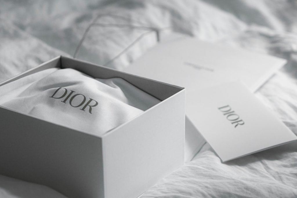 dior-box-with-cloth-and-card-on-white-fabric-dgldh2qfx4q